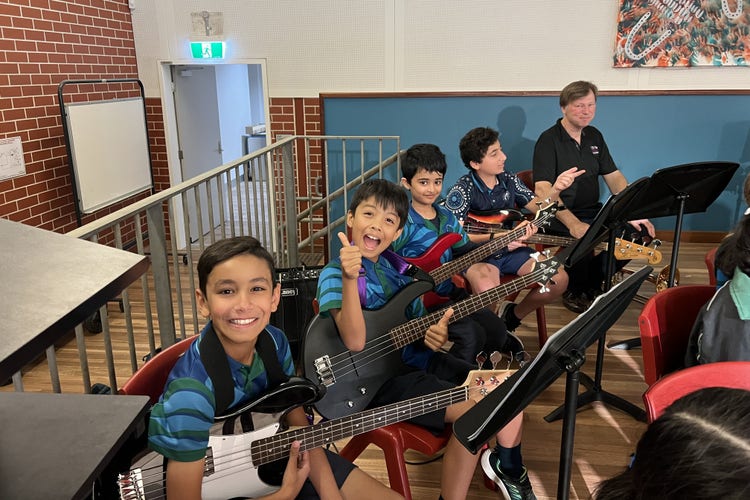 Students sitting on the stage waiting for their band performance to begin.