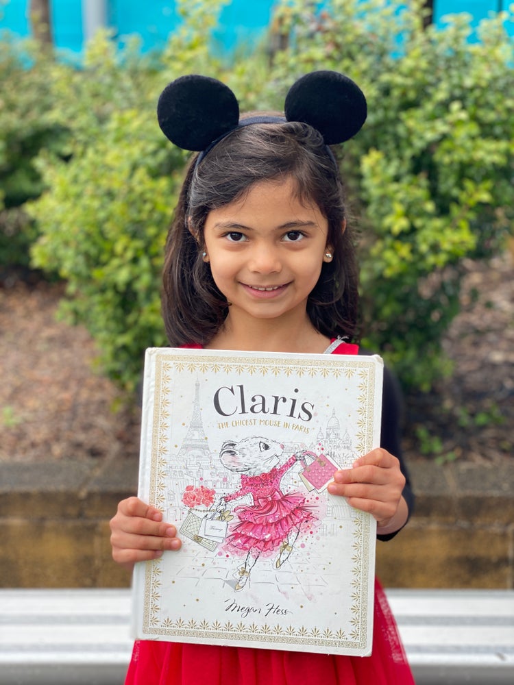 Student dressed as a mouse holding a story book about a mouse.